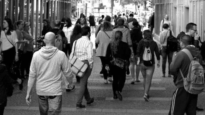 Foto en blanco y negro de personas caminando en la vereda.